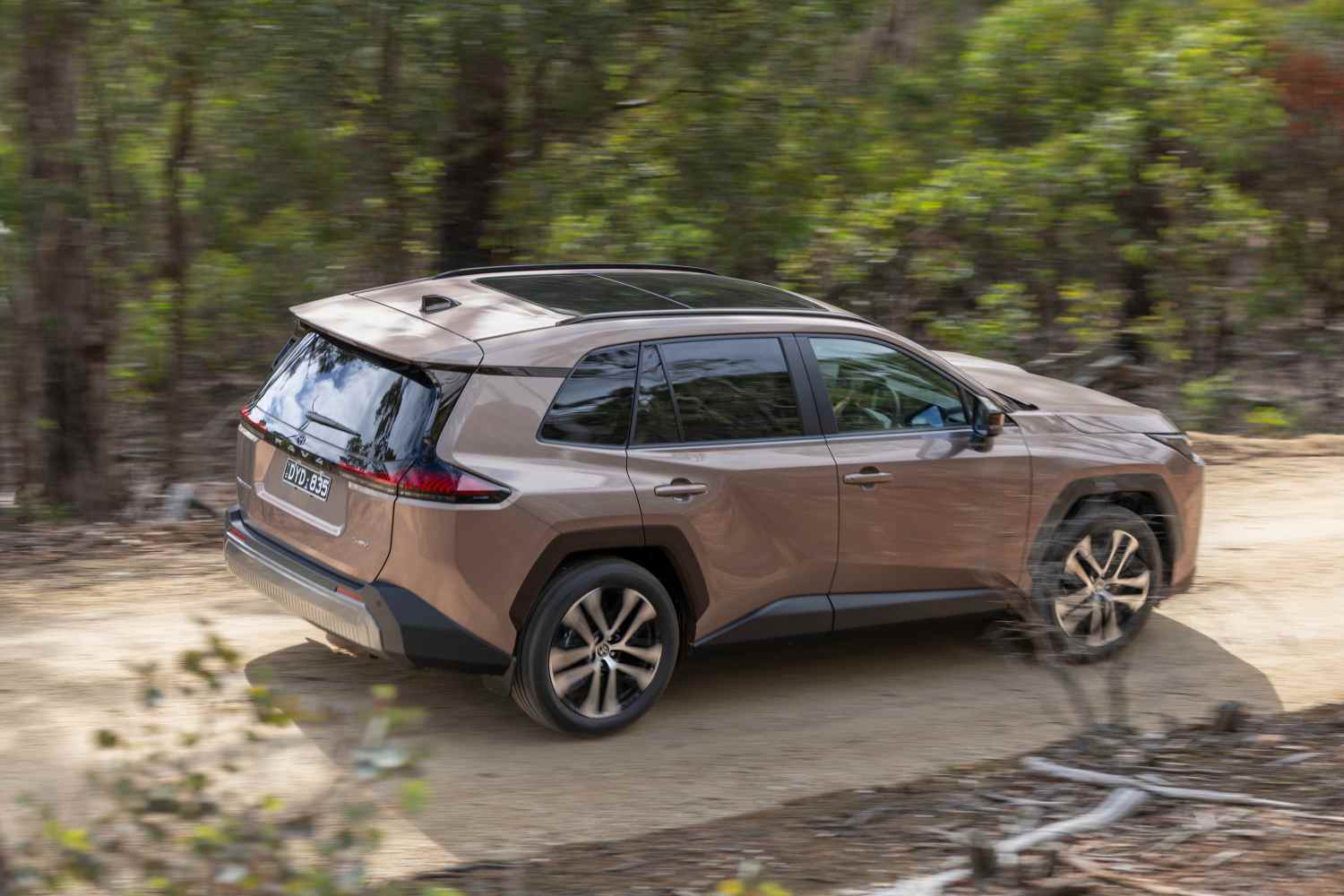 2026 Toyota RAV4 Cruiser AWD Hybrid rear quarter driving on dirt road 1